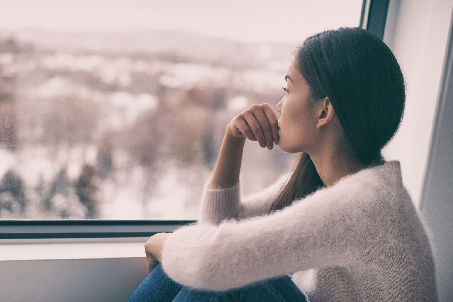 Frau mit Winterdepression am Fenster